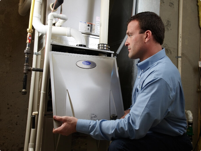 Technician servicing a Carrier furnace for fall heating maintenance